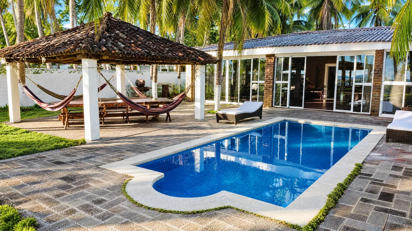 Casa con ventanales, piscina y kiosko con hamacas
